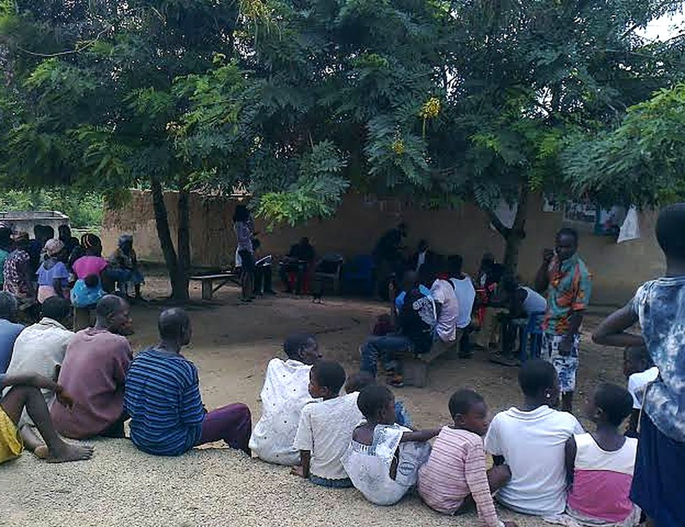 A community gathering under trees during an EI4HD community health and needs assessment session in Zambia.